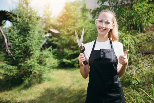 Attractive,Gardener,Girl,In,An,Apron,And,Safety,Glasses,Holds